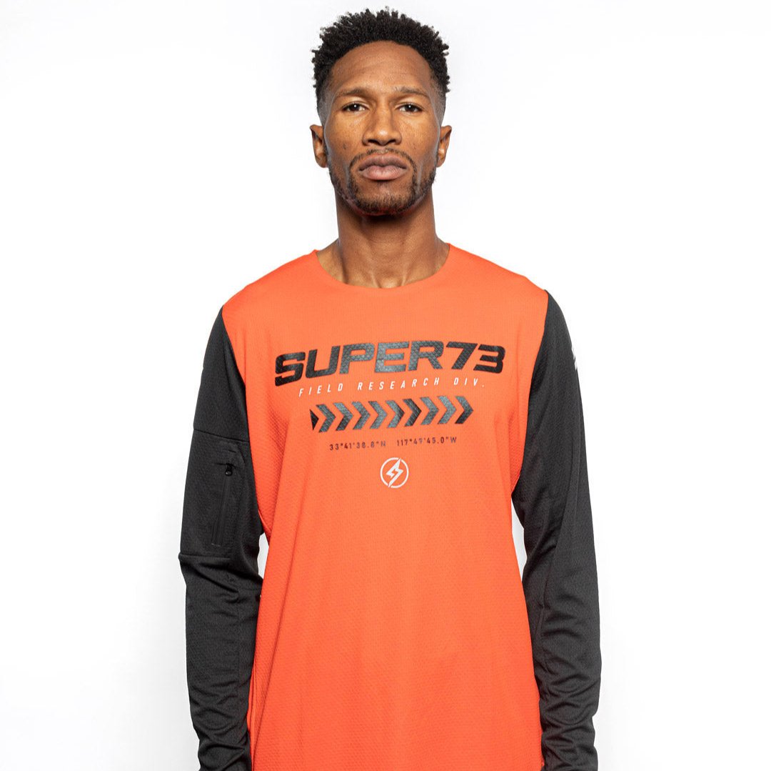 Male model front view of orange Premium long sleeve athletic moto hoon jersey. @color_blood orange