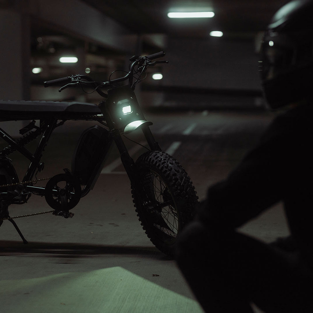 Lifestyle image of a man in a helmet sitting in front of a SUPER73-R Adventure SE ebike in Bandit
