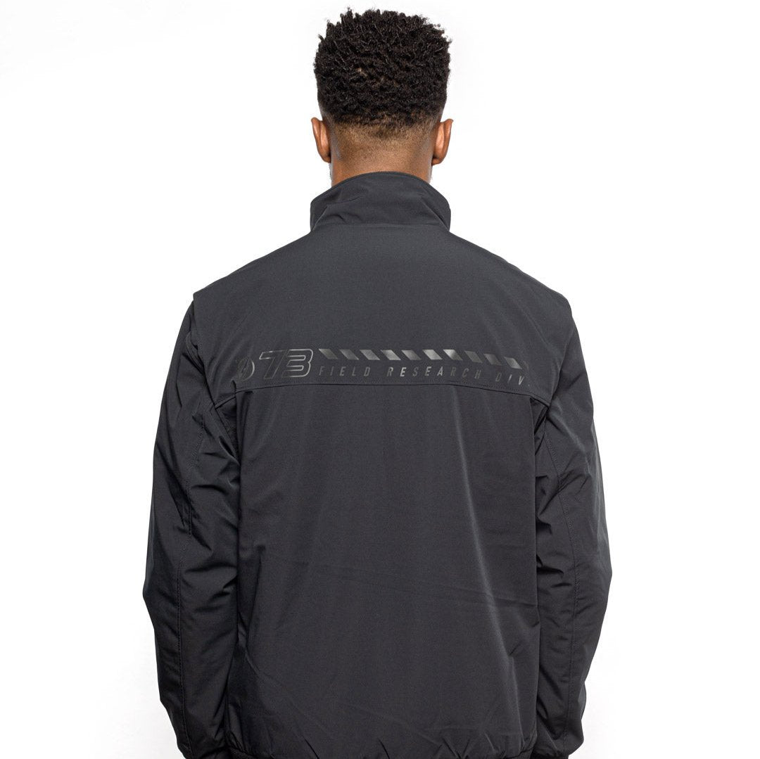 Back view of Male model wearing Royce Harrington Jacket in black colorway. @color_black
