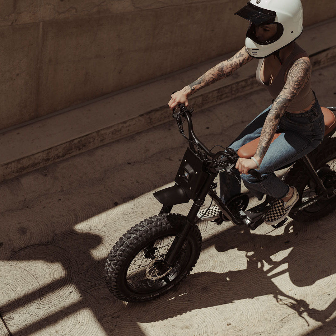 Lifestyle image of a woman in a helmet riding a SUPER73-Z Adventure SE ebike in Palladium